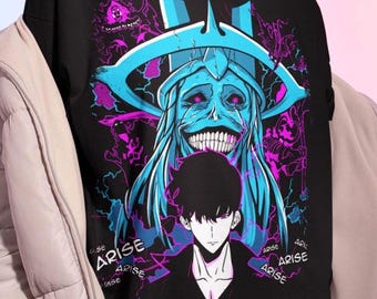 May include: Black t-shirt featuring a graphic design with a blue and purple monster and a male anime character. The word "ARISE" is printed in white. The shirt is worn by a person.