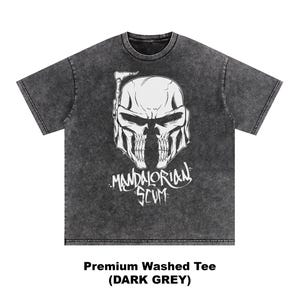 Pu&ograve; includere: T-shirt grigio scuro lavato con una grafica bianca di un casco a forma di teschio e la scritta "Mandalorian Scum". La maglietta &egrave; di colore grigio scuro e ha un aspetto invecchiato. Il testo "Premium Washed Tee (DARK GREY)" &egrave; in basso.