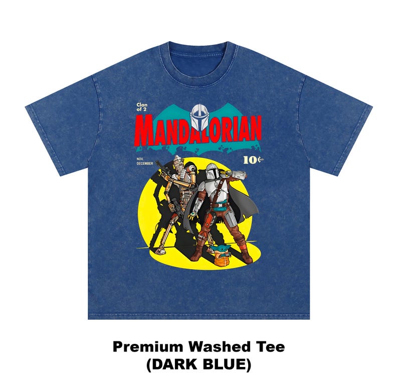 May include: Dark blue premium washed tee featuring a comic book style graphic of The Mandalorian and another character. The graphic includes the word "MANDALORIAN" in red, a yellow background, and the text "Clan of 2".