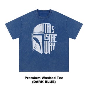 May include: Dark blue t-shirt featuring a white helmet graphic and the text "THIS IS THE WAY". A premium washed tee.