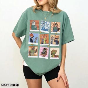 May include: Light green t-shirt featuring a grid of cartoon character images in polaroid-style frames. The images include various animal characters in different outfits and settings. The text "LIGHT GREEN" is at the bottom of the image.