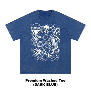 Puede incluir: Camiseta lavada premium azul oscuro con un gr&aacute;fico blanco de un personaje con casco y arma, y una peque&ntilde;a criatura. El texto "Premium Washed Tee (DARK BLUE)" est&aacute; impreso en la parte inferior.
