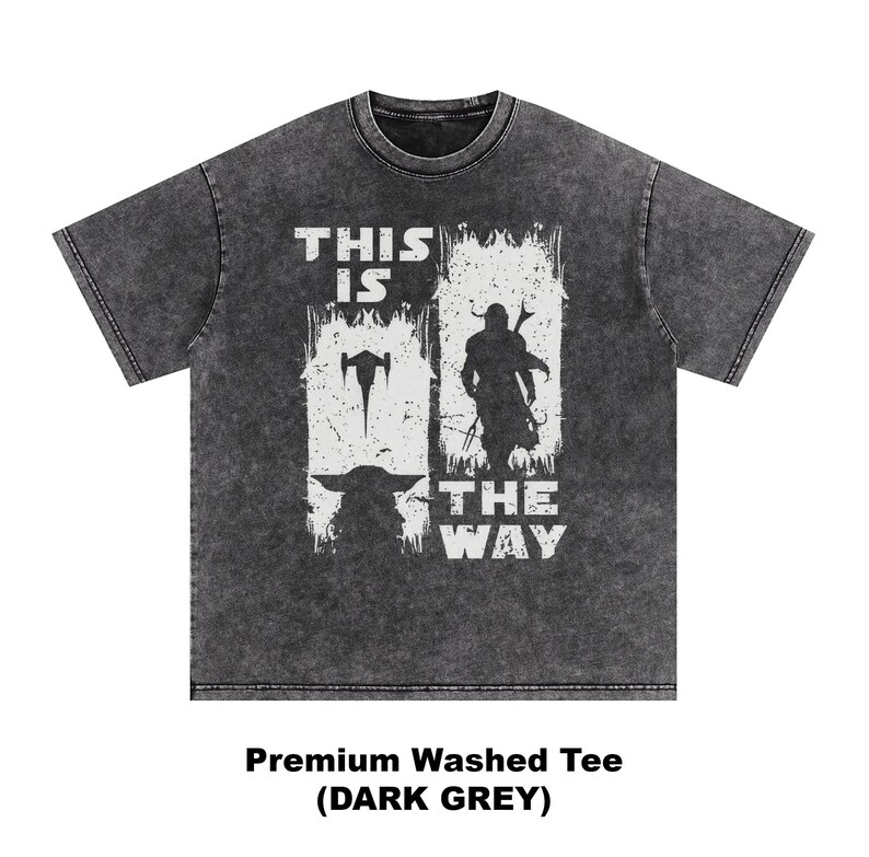 May include: Dark grey t-shirt with a white graphic featuring a silhouette of a character and the text "THIS IS THE WAY". The shirt also has an image of a spaceship and a small creature. The shirt is labeled "Premium Washed Tee (DARK GREY)".