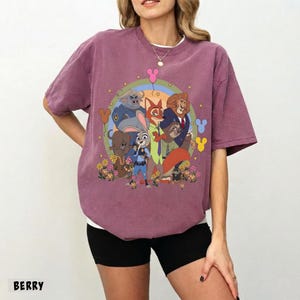 May include: Berry-colored t-shirt featuring a colorful graphic of characters from the animated movie Zootopia. The design includes Judy Hopps, Nick Wilde, and other characters. The word "BERRY" is printed at the bottom of the shirt.