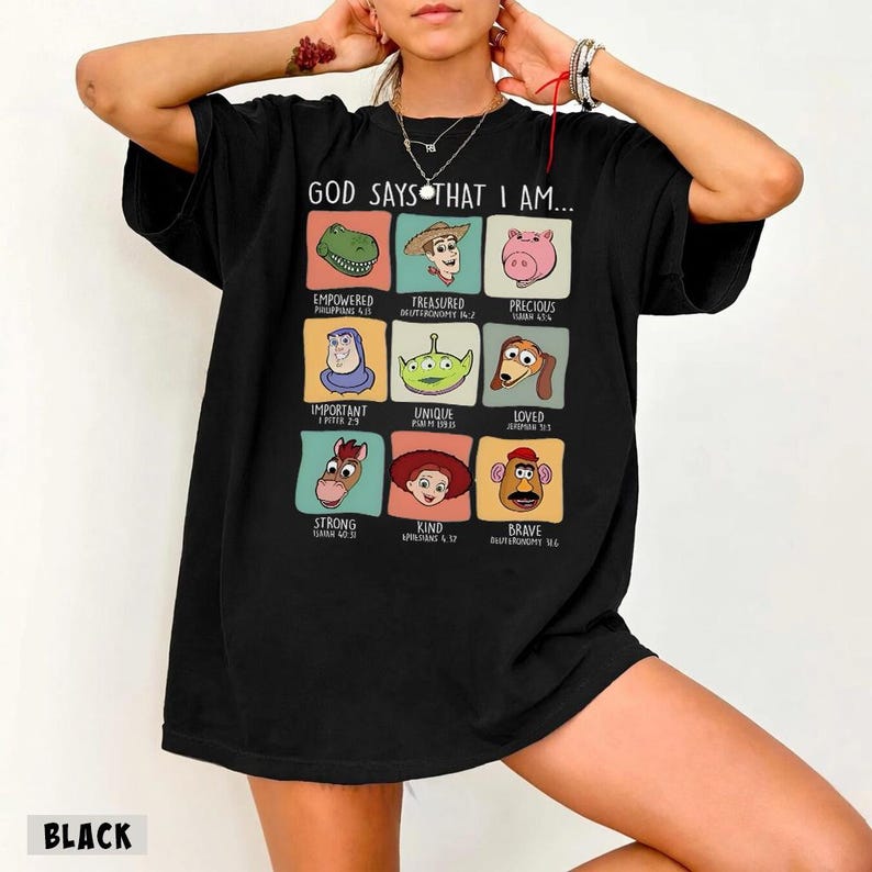 May include: Black t-shirt with the text "GOD SAYS THAT I AM..." and cartoon character images with words like "Empowered," "Treasured," and "Precious." The shirt also has the word "BLACK" at the bottom.