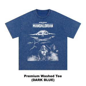 May include: Dark blue t-shirt featuring a graphic from the Star Wars series, "The Mandalorian." The design includes the text "STAR WARS THE MANDALORIAN" above an image of Grogu and the Mandalorian. The shirt also has the text "Premium Washed Tee (DARK BLUE)".