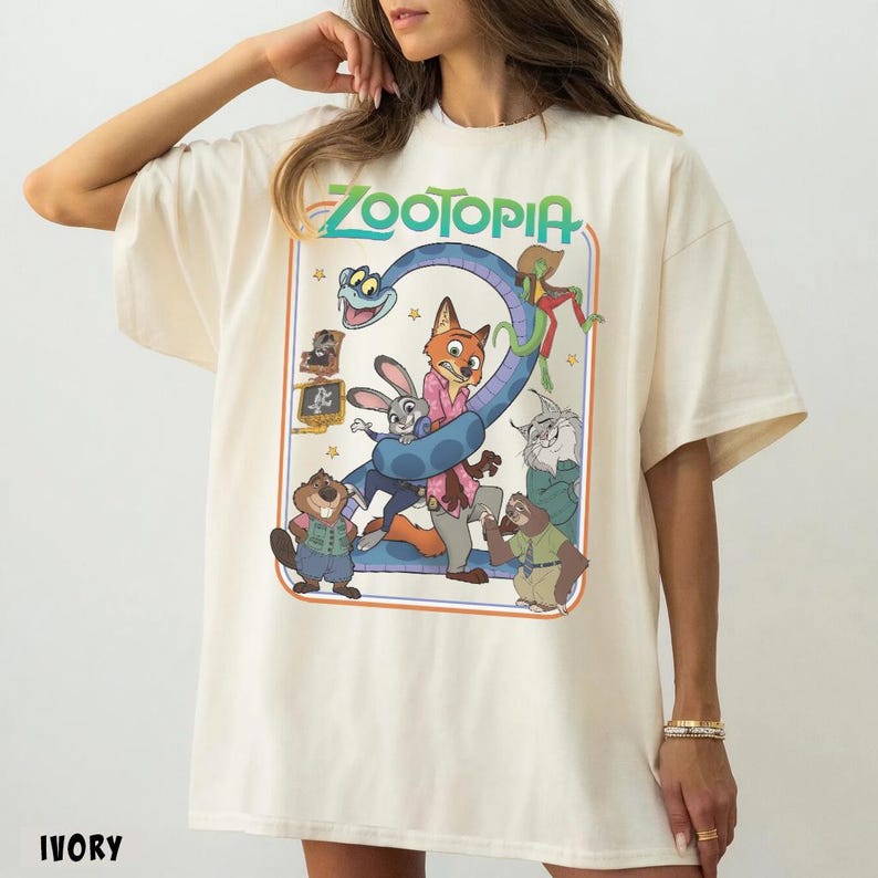 以下が含まれることがあります： アイボリー色のTシャツ。映画「ズートピア」のカラフルなグラフィックが特徴です。「ズートピア」のタイトルは緑色で、青いヘビと漫画のキャラクターが描かれています。半袖でゆったりとしたフィット感です。