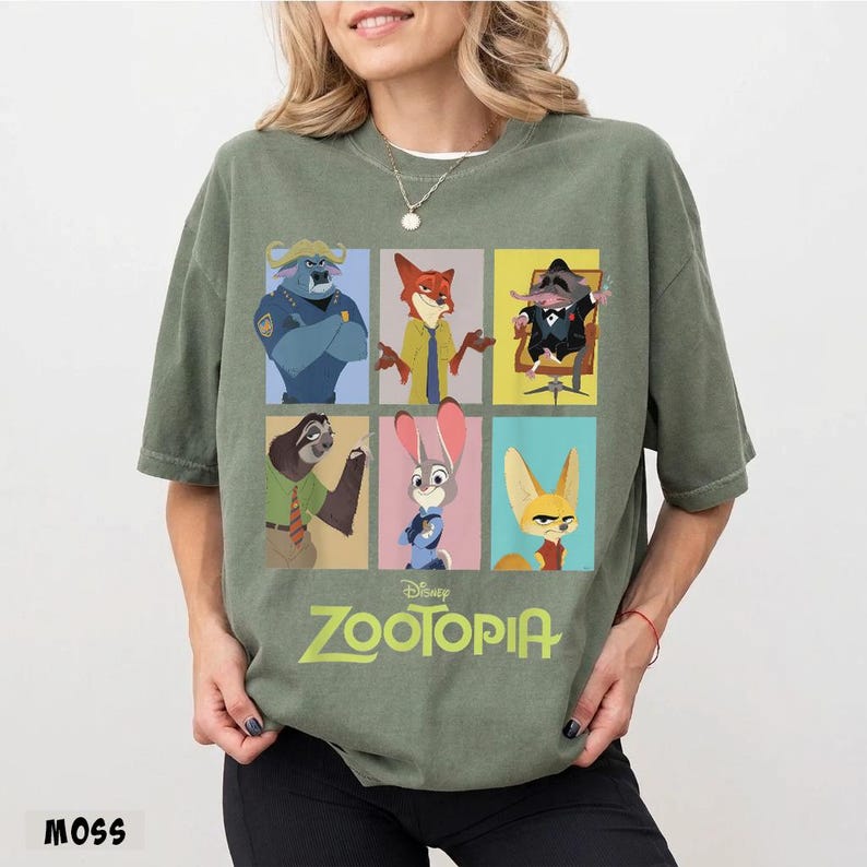 May include: A moss green t-shirt featuring a grid of six colorful character portraits from the Disney movie Zootopia. The movie title is printed in a light green font below the portraits. The word "MOSS" is printed in the bottom left corner.