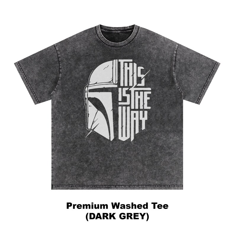 May include: Dark grey t-shirt with a white graphic of a helmet and the text "THIS IS THE WAY." The shirt is a premium washed tee in dark grey.