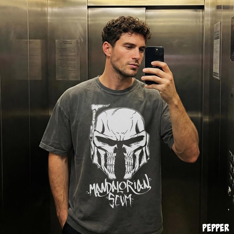 Pu&ograve; includere: T-shirt grigio scuro con un design a teschio bianco, un casco Mandaloriano e la scritta "Mandalorian Scum". La maglietta ha un aspetto vintage slavato e una vestibilit&agrave; rilassata.