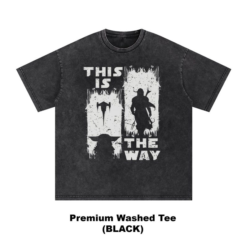May include: Black washed tee featuring a white graphic with the text "THIS IS THE WAY" and images of a spaceship, a character with a weapon, and a silhouette of a character. The shirt is a premium washed tee.