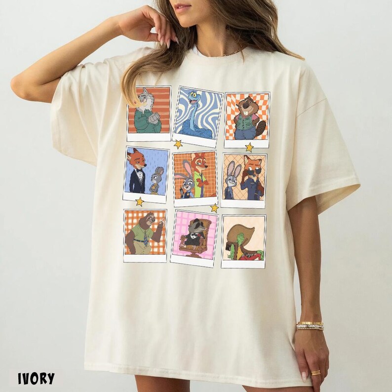 May include: Ivory-colored t-shirt featuring a grid of cartoon character portraits in polaroid-style frames. The illustrations depict various animals in different outfits and poses. The word "IVORY" is printed at the bottom of the shirt.