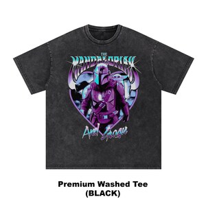 May include: Black washed tee featuring a graphic of The Mandalorian and Grogu in a heart-shaped design. The design includes the text "The Mandalorian" and "And Grogu" in a stylized font. The shirt is labeled "Premium Washed Tee (BLACK)".