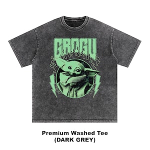 May include: Dark grey premium washed tee featuring a graphic of Grogu, with the word "GROGU" above the image. The design includes a green image of Grogu, lightning bolts, and flames. The shirt is dark grey.