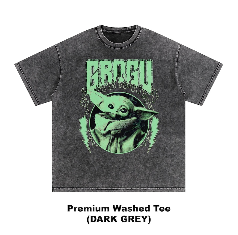May include: Dark grey premium washed tee featuring a graphic of Grogu, with the word "GROGU" above the image. The design includes a green image of Grogu, lightning bolts, and flames. The shirt is dark grey.