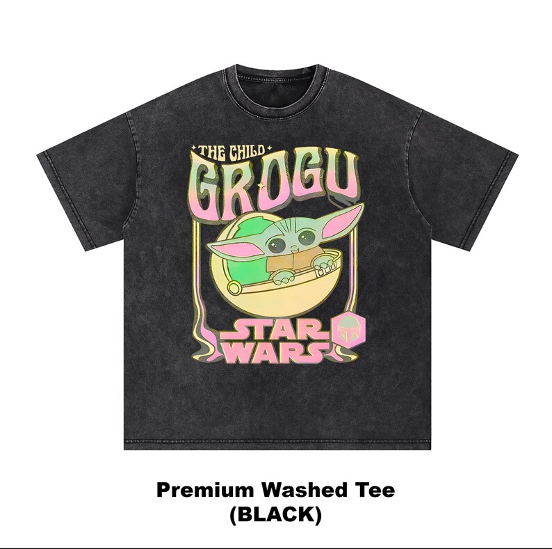 May include: Black washed tee featuring a Grogu graphic from Star Wars. The design includes the words "THE CHILD" and "GROGU" in a colorful, outlined font, with Grogu in a pod. The Star Wars logo is at the bottom.
