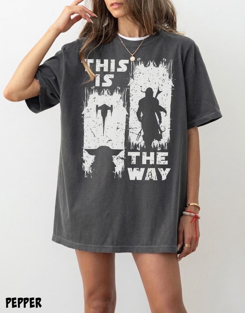 May include: Dark gray t-shirt with a white graphic featuring silhouettes of characters and the text "THIS IS THE WAY". The shirt has a relaxed fit and a vintage look.