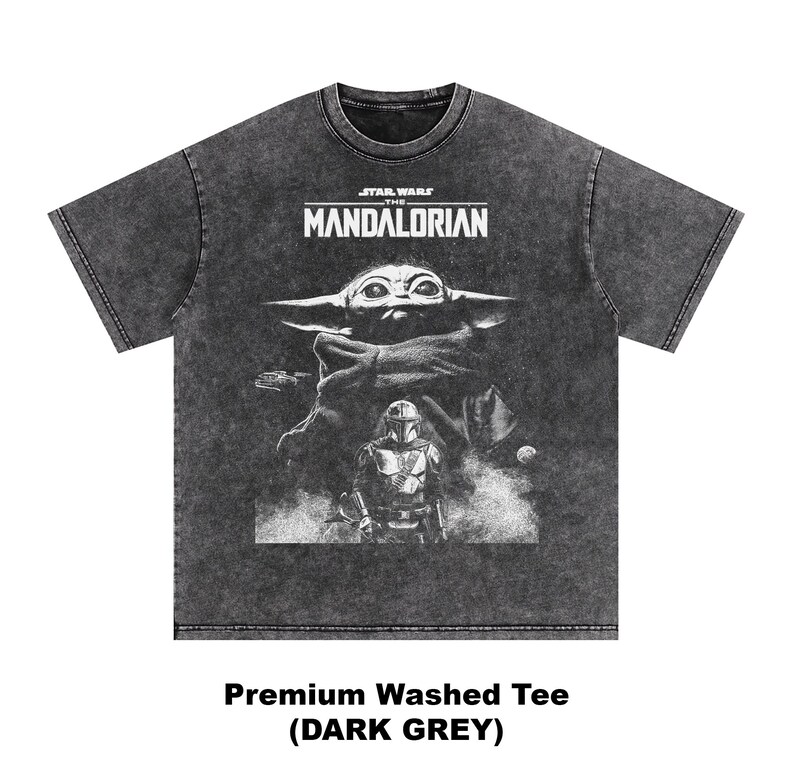 May include: Dark grey, washed t-shirt featuring a graphic from The Mandalorian. The design includes the show's logo, Grogu, and the Mandalorian. The text at the bottom reads "Premium Washed Tee (DARK GREY)".