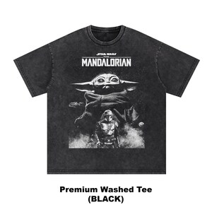 May include: Black washed tee featuring a graphic of The Mandalorian and Grogu from Star Wars. The design includes the text "STAR WARS THE MANDALORIAN" above the characters. The shirt is labeled "Premium Washed Tee (BLACK)".