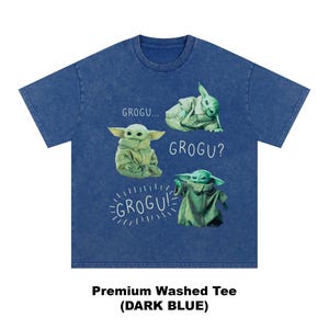 May include: Dark blue premium washed tee featuring four Grogu images with the text "GROGU...", "GROGU?", and "GROGU!". The images show Grogu in different poses. The shirt is a dark blue color.