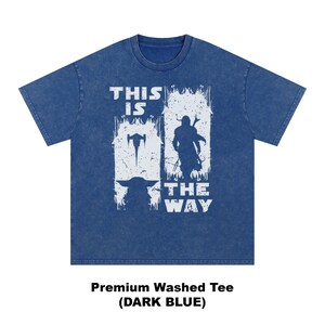 May include: Dark blue t-shirt with a white graphic featuring a spaceship, a silhouette of a character, and the text "THIS IS THE WAY". The shirt is a premium washed tee.