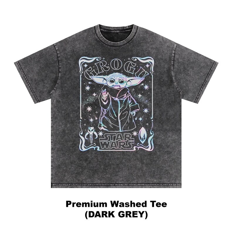 May include: Dark grey t-shirt featuring a Grogu graphic from Star Wars. The design includes Grogu, stars, and the Star Wars logo in a holographic style. The shirt is a premium washed tee.