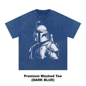 K&ouml;nnte beinhalten: Dunkelblaues Premium-Wasch-T-Shirt mit einer wei&szlig;en Illustration einer Figur mit Helm. Die Grafik ist mittig auf der Vorderseite platziert. Der Text darunter lautet "Premium Washed Tee (DARK BLUE)".