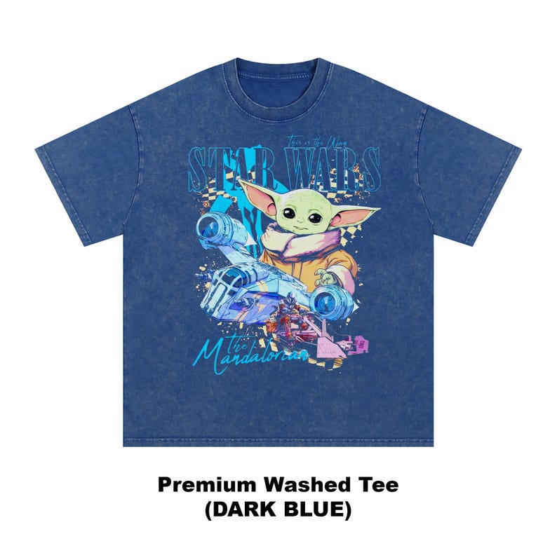 May include: Dark blue premium washed tee featuring a graphic of Grogu from The Mandalorian, with the text "Star Wars" and "The Mandalorian". The graphic includes a spaceship and Grogu in a tan coat. The shirt is a dark blue colour.