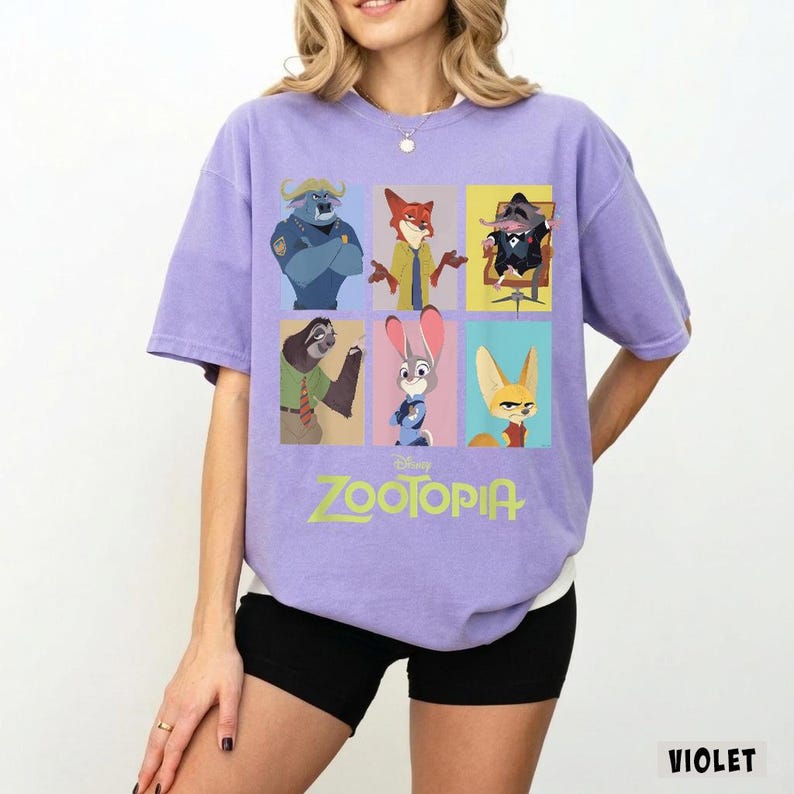 May include: Violet-colored Zootopia t-shirt featuring a grid of character illustrations from the Disney movie. The shirt displays the Zootopia logo in green. The shirt is a short-sleeved, crew neck style.