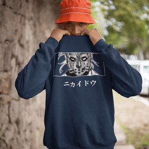 May include: Navy blue sweatshirt featuring a detailed graphic of a masked character with the Japanese text "ニカイドウ" in white. The sweatshirt is a solid color, and the graphic is in a rectangular frame.