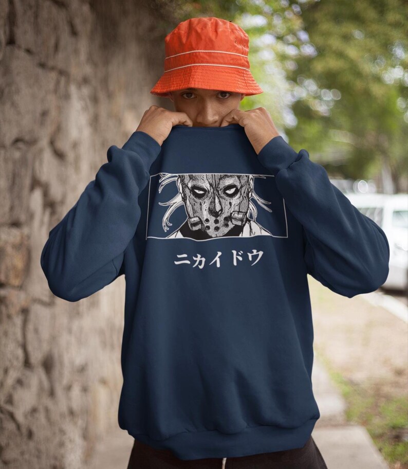 May include: Navy blue sweatshirt featuring a detailed graphic of a masked character with the Japanese text "ニカイドウ" in white. The sweatshirt is a solid color, and the graphic is in a rectangular frame.
