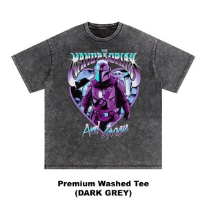 May include: Dark grey premium washed tee featuring a graphic of The Mandalorian and Grogu in purple and blue. The design is set against a heart-shaped background. The text "The Mandalorian" and "And Grogu" are also visible.
