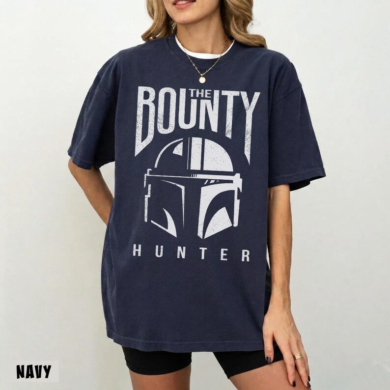 Puede incluir: Camiseta azul marino con la inscripci&oacute;n blanca "THE BOUNTY HUNTER" y un dise&ntilde;o de casco. La camiseta tiene un corte holgado y mangas cortas.