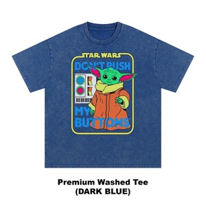 May include: Dark blue premium washed tee featuring a graphic of a green alien character in an orange coat. The graphic includes the text "STAR WARS DON'T PUSH MY BUTTONS". The tee is a crew neck style.