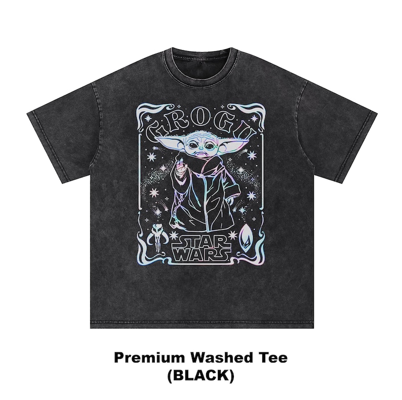 May include: Black washed tee featuring a graphic of Grogu from Star Wars. The design includes the text "Grogu" and "Star Wars" with a colorful, holographic effect. The shirt is a premium washed tee.