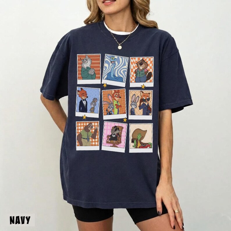 May include: Navy blue t-shirt featuring a grid of cartoon character portraits. Each portrait is framed in white with a star in each corner. The word "NAVY" is printed at the bottom of the shirt.