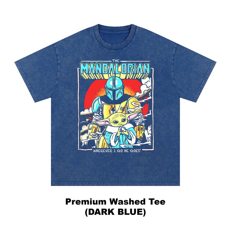 May include: Dark blue premium washed tee featuring a graphic of The Mandalorian and Grogu. The design includes the text "THE MANDALORIAN" and "WHEREVER I GO HE GOES!" in a retro style. The shirt is dark blue.