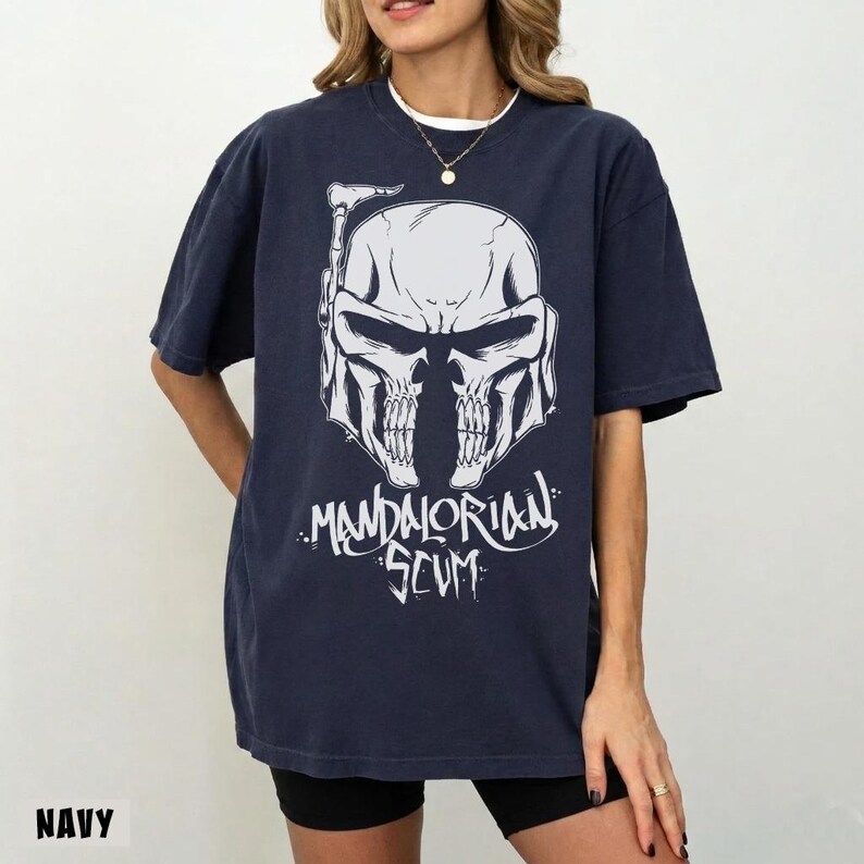 Pu&ograve; includere: T-shirt blu navy con grafica bianca di un casco a forma di teschio e la scritta "Mandalorian Scum". La maglietta ha maniche corte e una vestibilit&agrave; ampia. La parola "NAVY" &egrave; stampata in basso a sinistra.