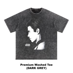 Op de afbeelding: Donkergrijs T-shirt met een zwart-wit profiel van een persoon. Het Star Wars-logo is links onderin zichtbaar. De tekst "Premium Washed Tee (DARK GREY)" staat onderaan het T-shirt.