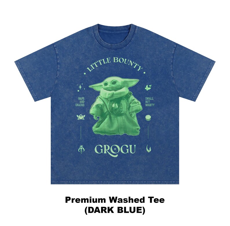 Op de afbeelding: Donkerblauwe t-shirt met een groene Grogu-afbeelding en de tekst "Little Bounty". Het ontwerp bevat de woorden "Naps and Snacks" en "Small but Mighty". Het shirt is gelabeld "Premium Washed Tee (DARK BLUE)".