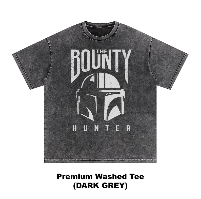 Puede incluir: Camiseta gris oscuro con un gr&aacute;fico desgastado. El dise&ntilde;o presenta las palabras "THE BOUNTY HUNTER" sobre un casco estilizado. La camiseta es una camiseta lavada de primera calidad.
