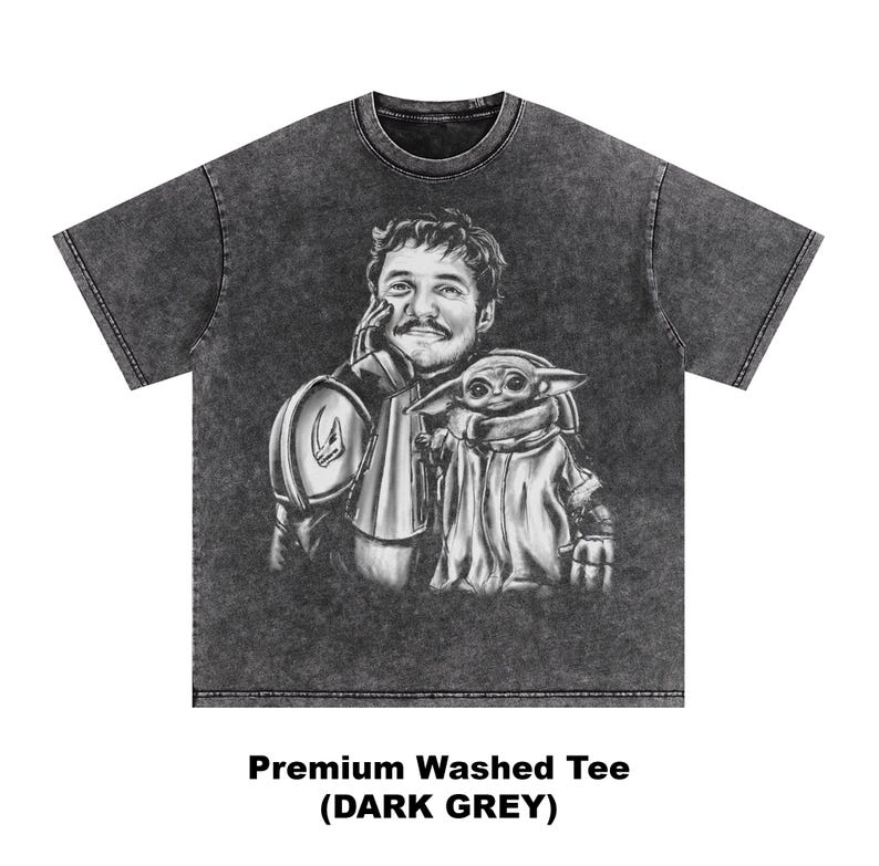 Puede incluir: Camiseta gris oscuro lavado con una ilustraci&oacute;n en blanco y negro de un hombre y una peque&ntilde;a criatura alien&iacute;gena. El hombre lleva una armadura y el alien&iacute;gena est&aacute; envuelto en una capa. El texto "Premium Washed Tee (DARK GREY)" est&aacute; impreso en la parte inferior.