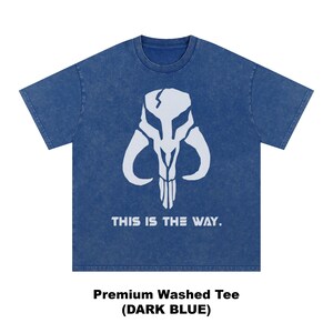 May include: Dark blue t-shirt featuring a white Mandalorian skull design. The text "THIS IS THE WAY" is printed below the graphic. The shirt is a premium washed tee.