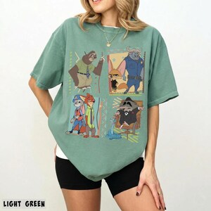 Puede incluir: Camiseta verde claro con un gr&aacute;fico colorido de personajes de una popular pel&iacute;cula animada. El dise&ntilde;o incluye un perezoso, un zorro, un b&uacute;falo, un conejo y un mapache. La camiseta es de material suave y tiene mangas cortas.