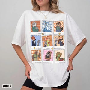 May include: White t-shirt featuring a grid of cartoon character portraits in polaroid-style frames. The illustrations depict various animals in colorful outfits, with a star graphic between each frame. The word "WHITE" is printed at the bottom left.