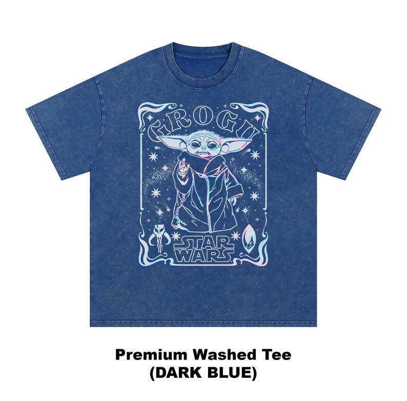 May include: Dark blue premium washed tee featuring a graphic of Grogu from Star Wars. The design includes the text "Grogu" and "Star Wars" in a decorative frame. The image is in a light blue and white color scheme.