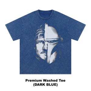 May include: Dark blue premium washed tee featuring a split face design. One side depicts a man's face, the other a Mandalorian helmet. The text at the bottom reads "Premium Washed Tee (DARK BLUE)".