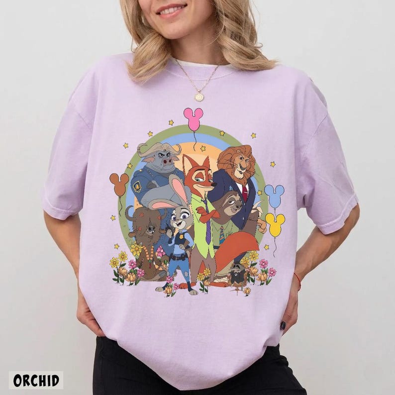 May include: Orchid-colored t-shirt featuring a colorful cartoon graphic of characters from a popular animated movie. The design includes a rainbow, stars, and Mickey Mouse-shaped balloons. The word "ORCHID" is printed at the bottom.