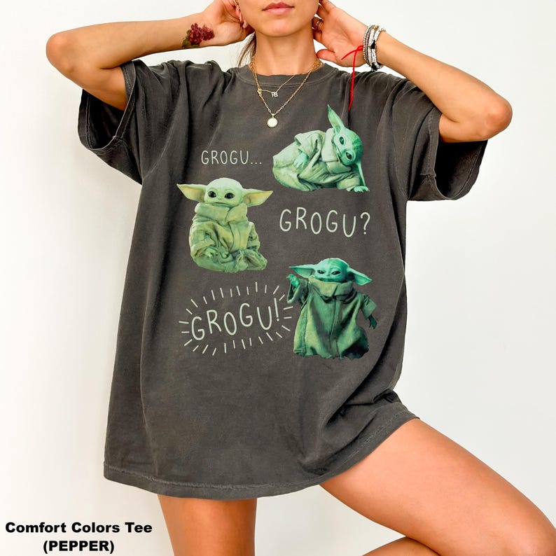 May include: Dark grey Comfort Colors tee featuring Grogu from The Mandalorian. The shirt displays Grogu in four different poses with the phrases "GROGU...", "GROGU?", and "GROGU!" in white text. The tee is a relaxed fit.