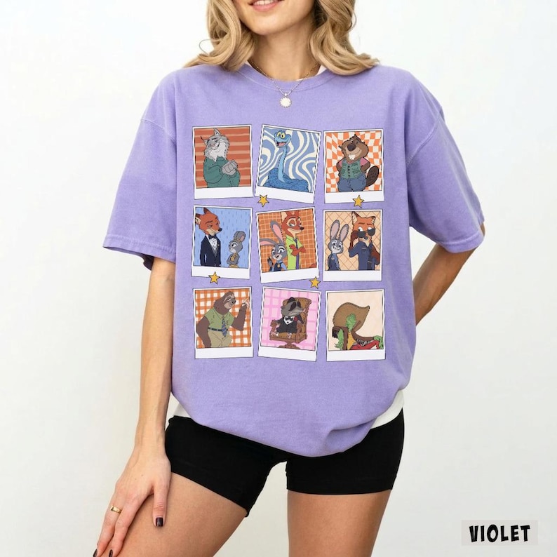 May include: Violet-colored t-shirt featuring a collage of cartoon character portraits. The portraits are in a grid pattern, each within a white-bordered frame. The shirt has a relaxed fit and short sleeves. The word "VIOLET" is printed at the bottom right.